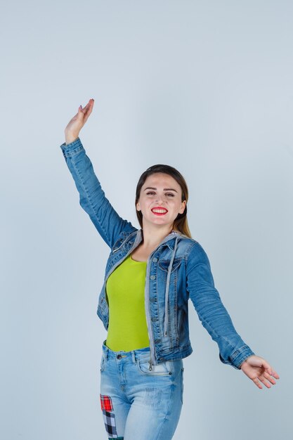 Giovane donna che si diverte, si gode la musica, balla in abito di jeans e sembra felice, vista frontale.