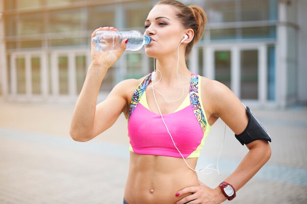 Giovane donna che si esercita all'aperto. L'acqua è molto importante nella dieta quotidiana