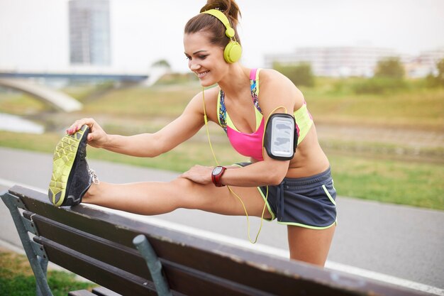 Giovane donna che si esercita all'aperto. La panca è un grande aiuto durante lo stretching