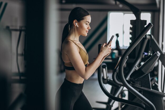 Giovane donna che si esercita alla palestra su ellittica