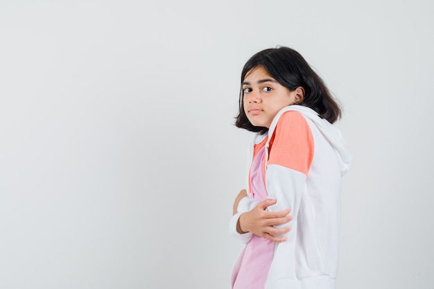 Giovane donna che si raffredda in giacca, camicia rosa e sembra fresca.