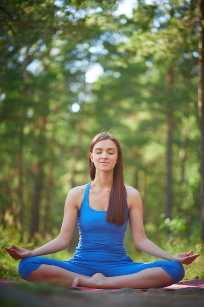 Giovane donna che si siede all&#39;aperto in posizione yoga