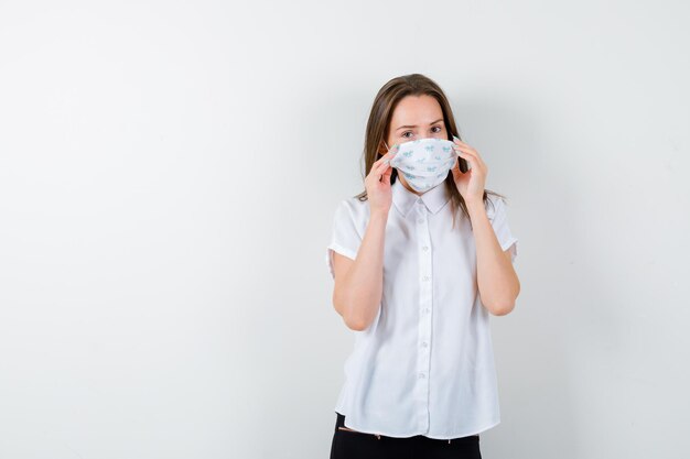 Giovane donna che si tiene per mano sulla sua maschera medica