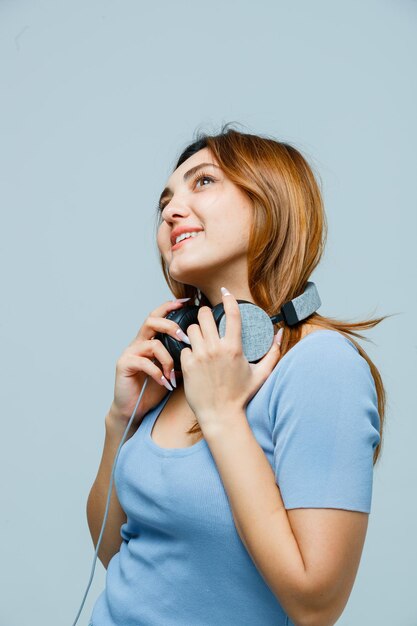 Giovane donna che si tiene per mano sulle cuffie mentre guarda in alto