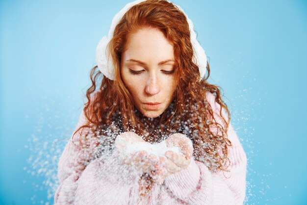 Giovane donna che soffia neve finta in studio shot