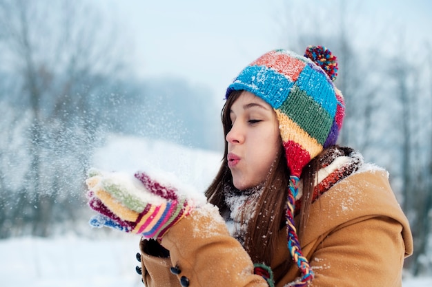 Giovane donna che soffia neve per allontanarsi