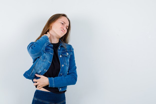 Giovane donna che soffre di dolore al collo in camicetta e sembra stanca