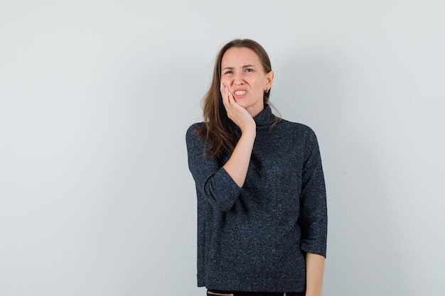 Giovane donna che soffre di mal di denti in camicia e sembra a disagio