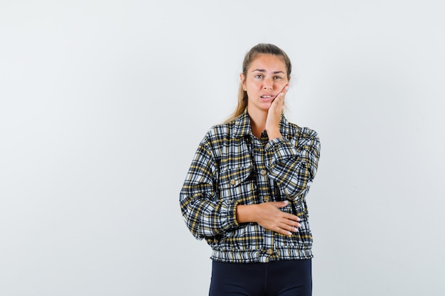 Giovane donna che soffre di mal di denti in maglietta, pantaloncini e sembra a disagio. vista frontale.