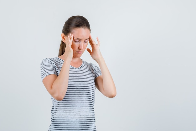 Giovane donna che soffre di mal di testa in t-shirt, vista frontale.