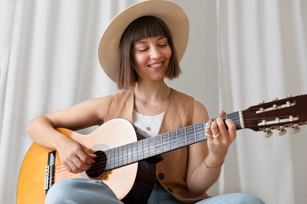 Giovane donna che suona la chitarra al chiuso