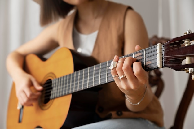 Giovane donna che suona la chitarra al chiuso