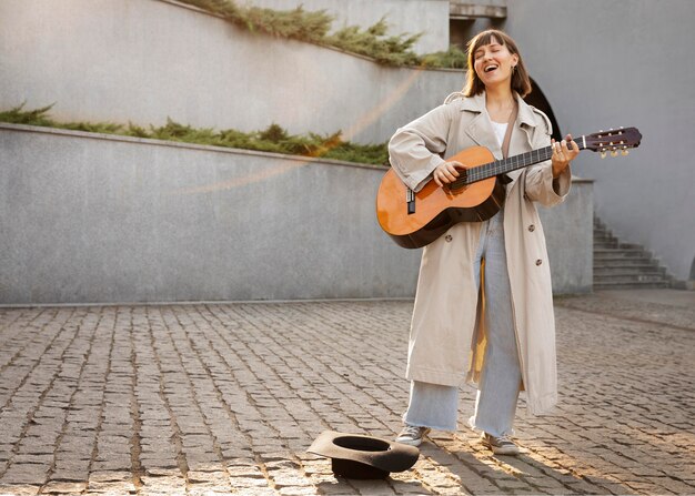 Giovane donna che suona la chitarra all'aperto con spazio di copia