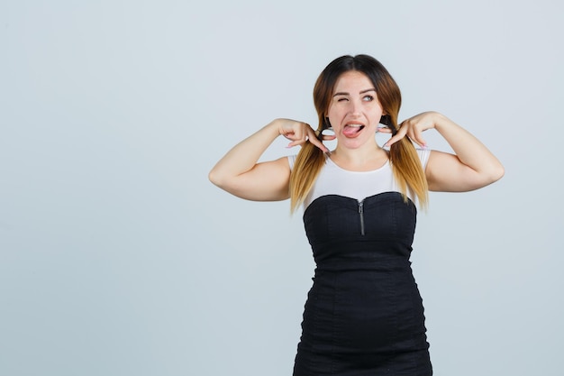 Giovane donna che tiene ciocche di capelli e tira fuori la lingua