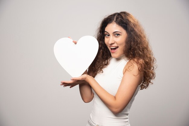 Giovane donna che tiene cuore di carta fatto a mano bianco. Foto di alta qualità