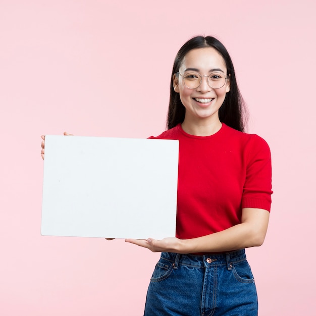 Giovane donna che tiene foglio di carta bianco