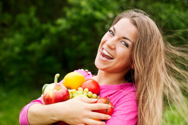 Giovane donna che tiene frutta e verdura