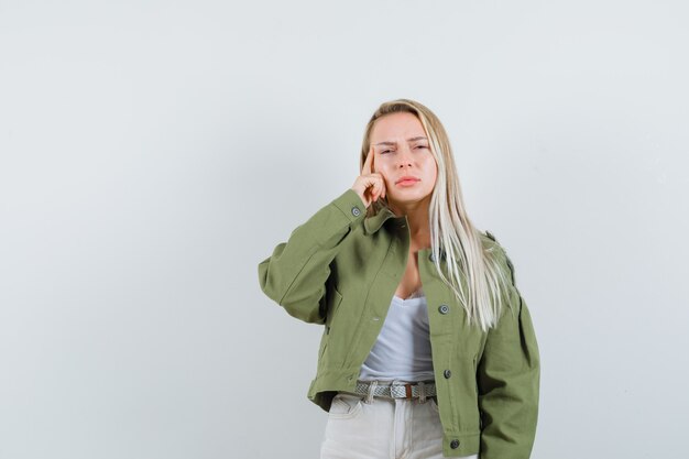 Giovane donna che tiene il dito sulle tempie in giacca, pantaloni e sembra esausta. vista frontale.