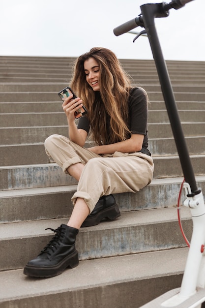 Giovane donna che tiene il suo telefono cellulare