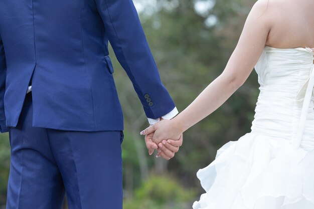 Giovane donna che tiene la mano dell'uomo mentre lo conduce sul giardino fiorito