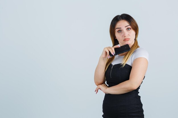 Giovane donna che tiene lo smartphone sotto il mento