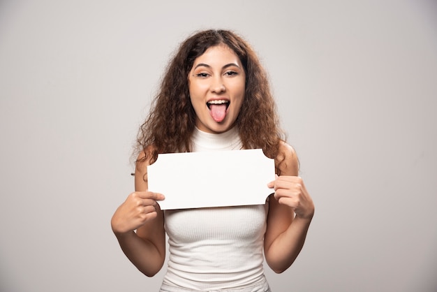 Giovane donna che tiene manifesto di discorso bianco vuoto vuoto. Foto di alta qualità