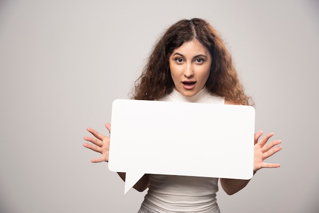 Giovane donna che tiene manifesto di discorso bianco vuoto vuoto. Foto di alta qualità