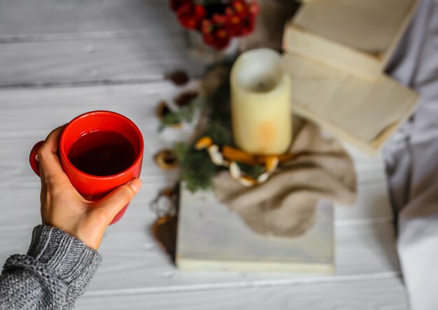 Giovane donna che tiene tazza rossa di tè nella sua camera da letto