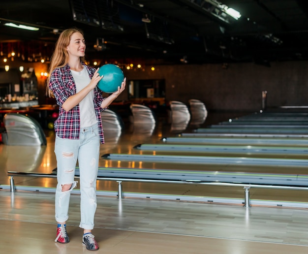 Giovane donna che tiene un colpo lungo della palla da bowling