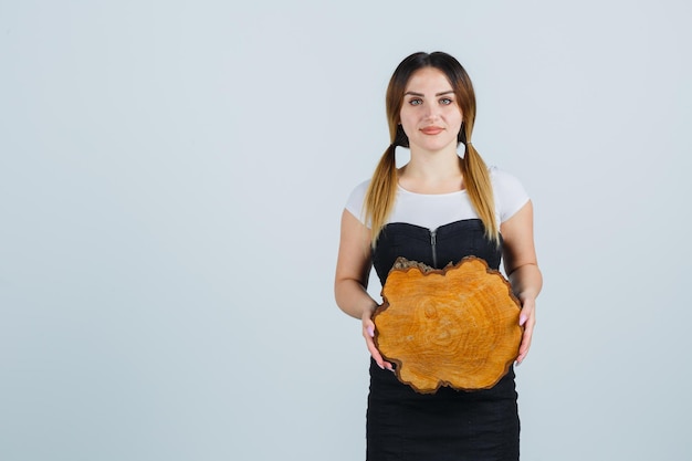 Giovane donna che tiene una fetta di tronco d'albero