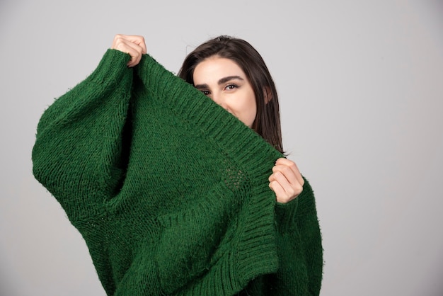 Giovane donna che tira il suo maglione su gray.