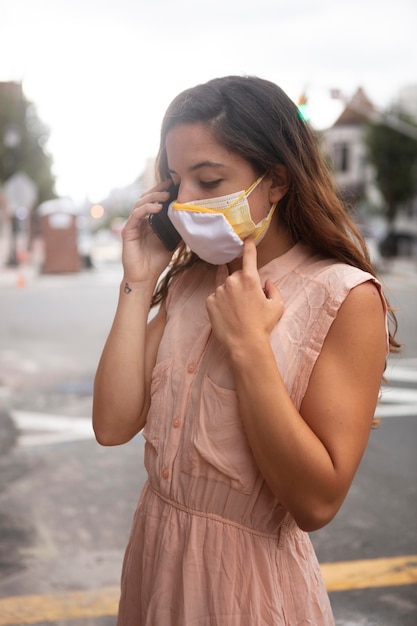 Giovane donna che tollera l'ondata di caldo mentre indossa una maschera medica