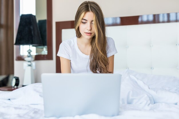 Giovane donna che usa il laptop sul letto a casa
