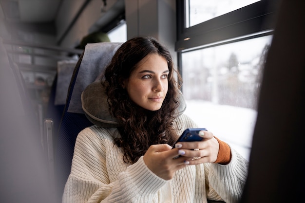 Giovane donna che usa il suo smartphone mentre viaggia in treno