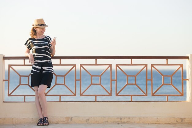 Giovane donna che utilizza app sulla strada del mare