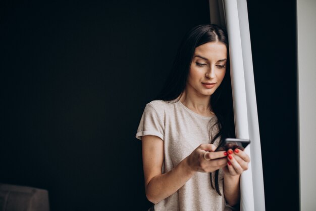 Giovane donna che utilizza il telefono a casa