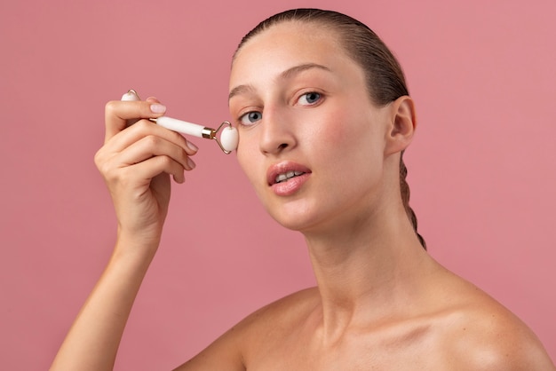 Giovane donna che utilizza la vista laterale del rullo facciale