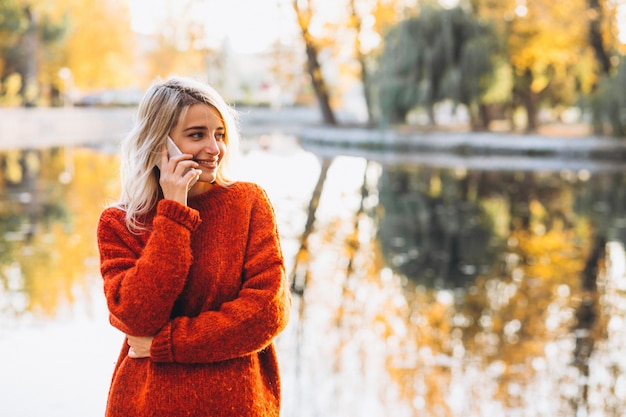 Giovane donna che utilizza telefono nel parco sul lago