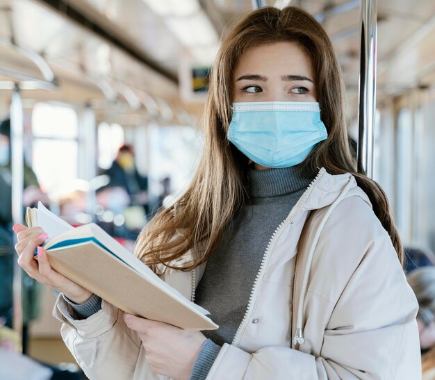 Giovane donna che viaggia in metropolitana leggendo un libro