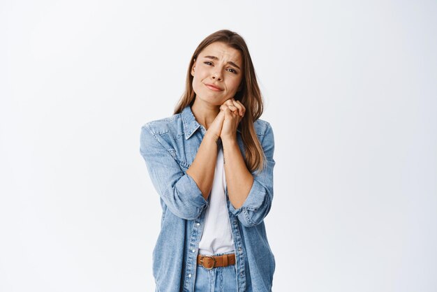 Giovane donna commovente così adorabile che guarda con simpatia e sentimenti commoventi a qualcosa di bello o romantico che lo desidera in piedi su sfondo bianco