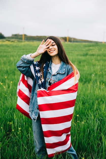 Giovane donna con bandiera americana soggiornare in campo