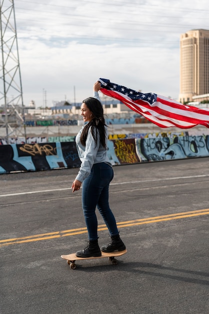 Giovane donna con bandiera usa su uno skateboard