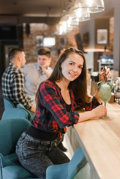 Giovane donna con bicchiere di cocktail al bar