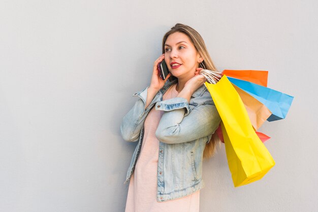 Giovane donna con borse della spesa parlando per telefono