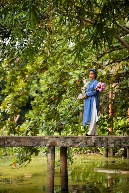 Giovane donna con bouquet di fiori che indossa un costume ao dai