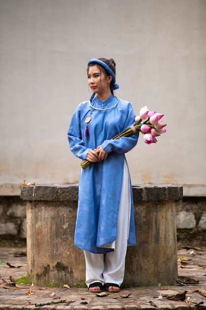 Giovane donna con bouquet di fiori che indossa un costume ao dai