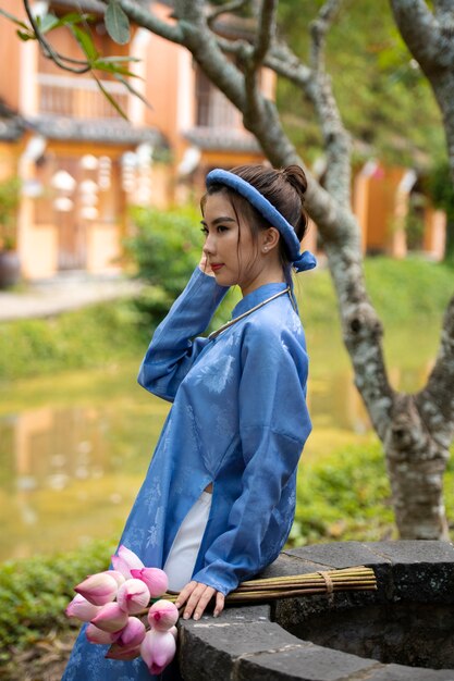 Giovane donna con bouquet di fiori che indossa un costume ao dai