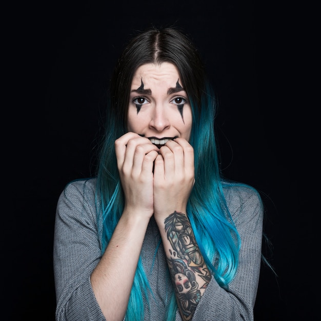 Giovane donna con capelli blu e faccia spaventata in posa in studio