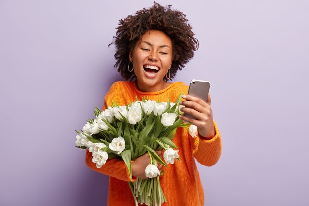 Giovane donna con capelli ricci che tiene il mazzo di fiori bianchi