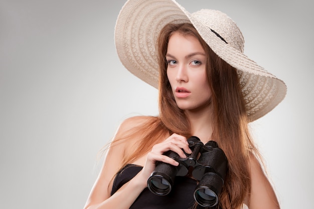 Giovane donna con cappello con binocolo